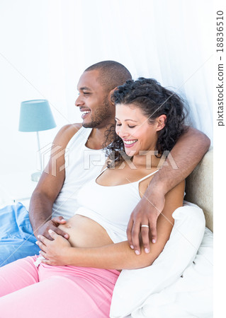 Husband sitting on bed with pregnant wife Husband sitting on bed with pregnant wife 18836510