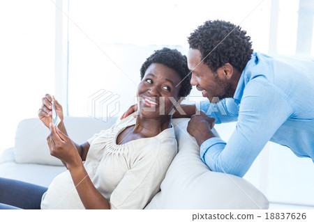 Pregnant woman showing photo to husband Pregnant woman showing photo to husband 18837626