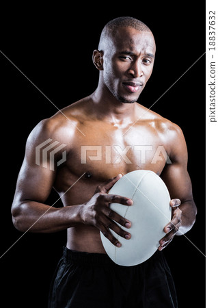Portrait of confident shirtless athlete holding rugby ball Portrait of confident shirtless athlete holding rugby ball 18837632