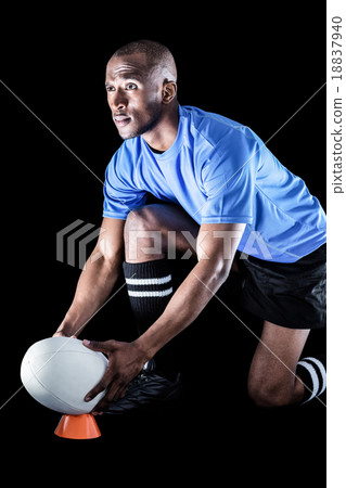 Sportsman looking away while keeping rugby ball on kicking tee 18837940