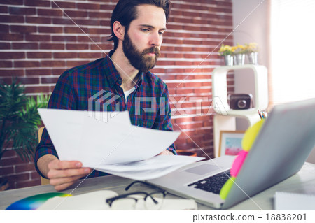 Creative businessman with documents using laptop Creative businessman with documents using laptop 18838201