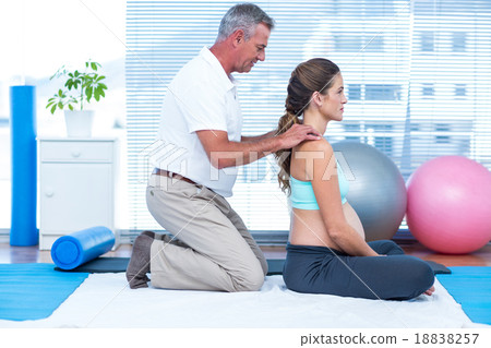 Gym trainer massaging pregnant woman Gym trainer massaging pregnant woman 18838257