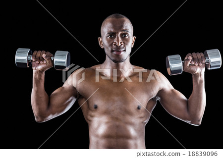 Portrait of athlete lifting dumbbell while exercising Portrait of athlete lifting dumbbell while exercising 18839096