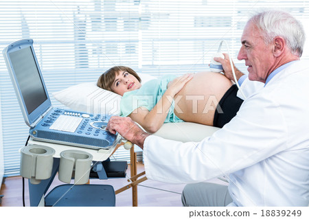 Pregnant woman and doctor looking at scan machine 18839249