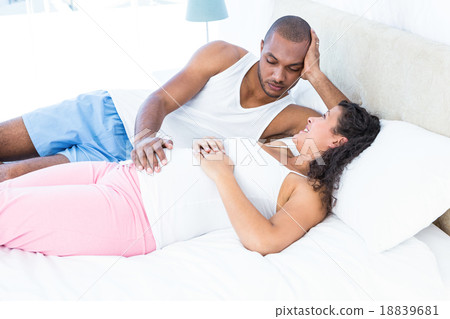 Happy pregnant wife relaxing with husband on bed Happy pregnant wife relaxing with husband on bed 18839681