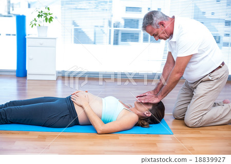 Therapist performing reiki on young woman Therapist performing reiki on young woman 18839927