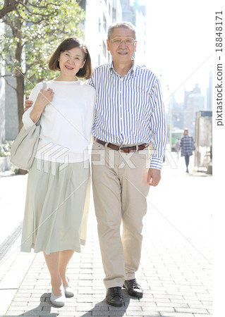 Two elderly couple walking along the street with a shoulder and happy Two elderly couple walking along the street with a shoulder and happy 18848171