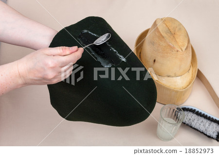 hatter applies an adhesive a felt hood for shaping 18852973