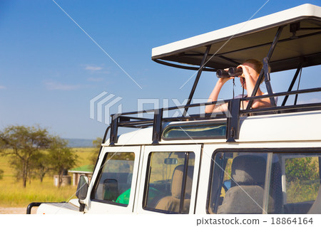 Woman on safari looking through binoculars. 18864164