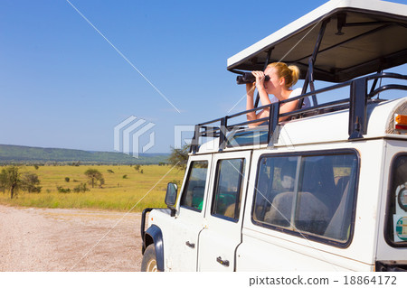 Woman on safari looking through binoculars. 18864172