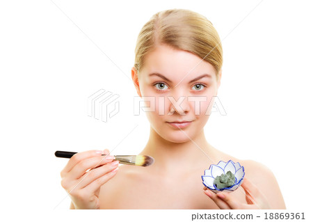 Skin care. Woman applying clay mud mask on face. 18869361