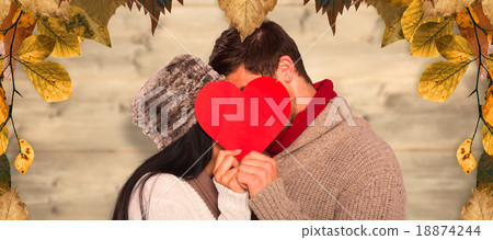 Composite image of young couple kissing behind red heart 18874244