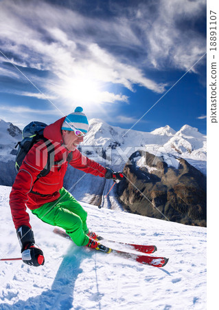 Skier skiing downhill in high mountains against bl Skier skiing downhill in high mountains against bl 18891107