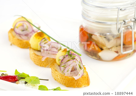 pickled herring in a glass jar with potato canapes pickled herring in a glass jar with potato canapes 18897444