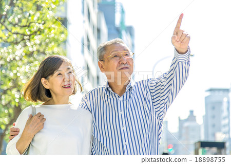 A couple pointing with a finger pointing while looking far away with two people shoulder at a street corner A couple pointing with a finger pointing while looking far away with two people shoulder at a street corner 18898755