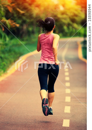 young fitness woman running at forest trail 18898944