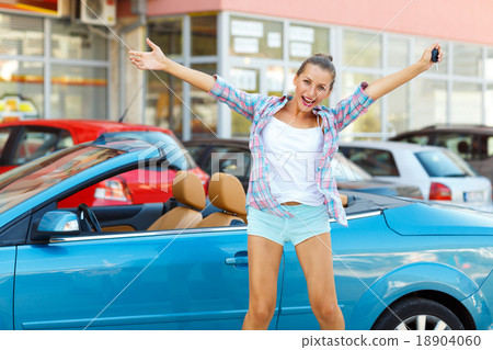Young emotional woman standing near a convertible with the keys Young emotional woman standing near a convertible with the keys 18904060