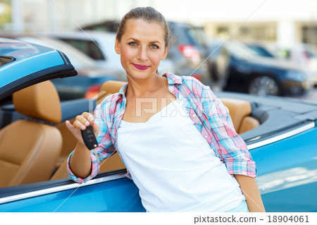 Young woman standing near a convertible with keys in hand Young woman standing near a convertible with keys in hand 18904061