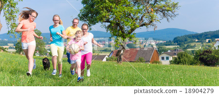 Father with children running on green meadow grass Father with children running on green meadow grass 18904279