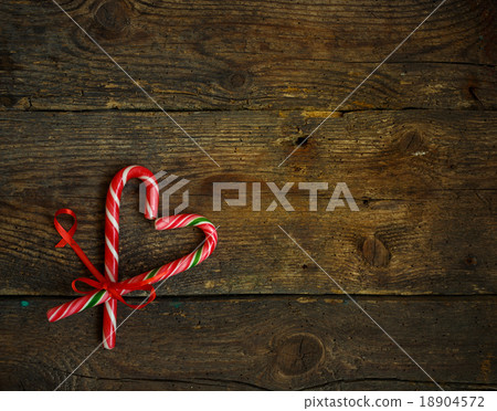 Candy canes in the heart shape on wood background Candy canes in the heart shape on wood background 18904572