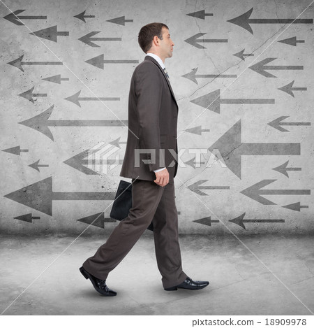 Businessman walking against arrows 18909978