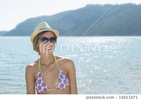 Happy girl at the beach with sun shining behind her Happy girl at the beach with sun shining behind her 18921871