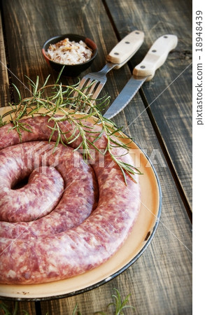 raw beef sausages on a cast-iron pan with rosemary 18948439