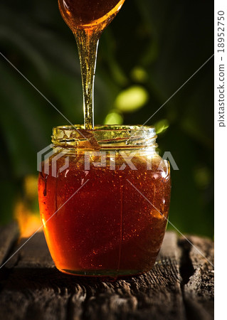 Close-up of flowing honey over yellow background Close-up of flowing honey over yellow background 18952750