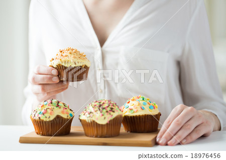 close up of woman with glazed cupcakes or muffins close up of woman with glazed cupcakes or muffins 18976456