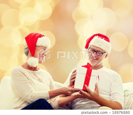 happy senior couple in santa hats with gift box happy senior couple in santa hats with gift box 18976880