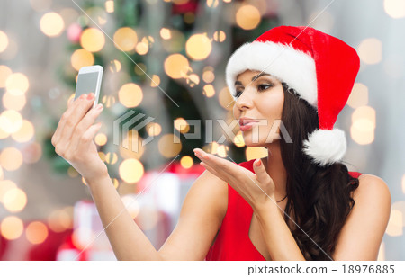 woman in santa hat taking selfie by smartphone woman in santa hat taking selfie by smartphone 18976885