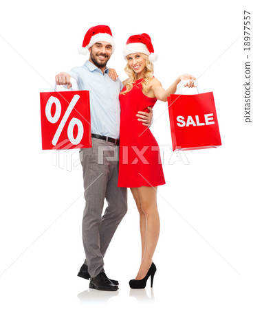 happy couple in santa hats with red shopping bags happy couple in santa hats with red shopping bags 18977557
