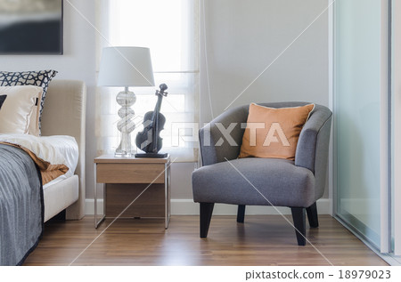 orange pillow on modern grey chair with bedside table and white orange pillow on modern grey chair with bedside table and white 18979023