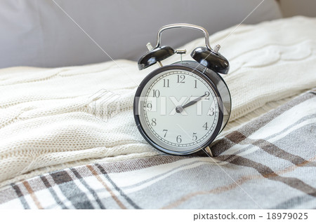 modern black alarm clock on bed in bedroom modern black alarm clock on bed in bedroom 18979025