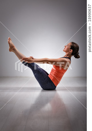 Woman practices yoga asana Paripurna navasana 18990637