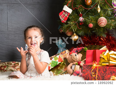 Cute  girl sitting on rug in Christmas interior 18992092