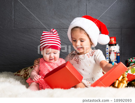 Cute kids on rug opening a Christmas present Cute kids on rug opening a Christmas present 18992093