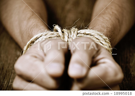 the hands of a young man tied with rope 18995018
