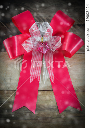 Red bow ribbon on wooden background 19002424