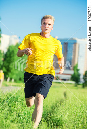 Sporty man jogging in city street park. Outdoor Sporty man jogging in city street park. Outdoor 19007964