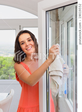 Brunette woman washing windows in house Brunette woman washing windows in house 19019332