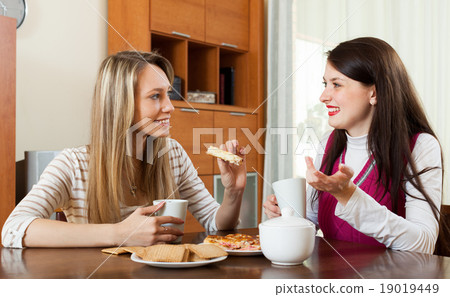 young women gossiping and drinking tea young women gossiping and drinking tea 19019449