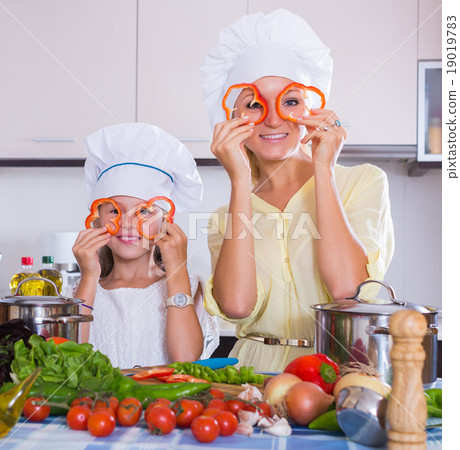 Woman and girl cooking veggies. Woman and girl cooking veggies. 19019783