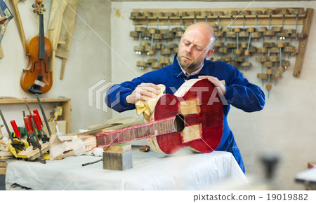 Craftsman holding unfinished guitar 19019882