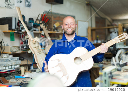 Craftsman holding unfinished guitar. 19019920