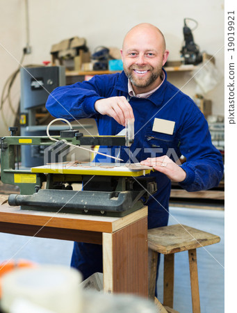 Woodworker on lathe in workroom 19019921