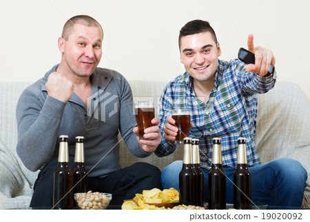 Two male sport fans watching game at home Two male sport fans watching game at home 19020092