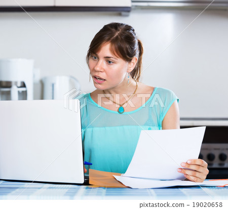 Unhappy housewife reading banking statement Unhappy housewife reading banking statement 19020658