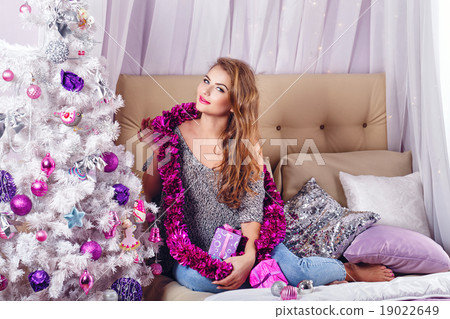 Girl sits on a couch near Christmas tree. Girl sits on a couch near Christmas tree. 19022649