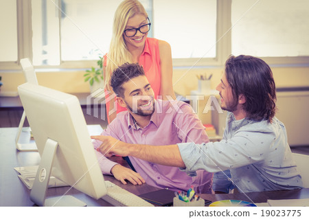 Businessman pointing on computer as smiling colleagues looking a Businessman pointing on computer as smiling colleagues looking a 19023775